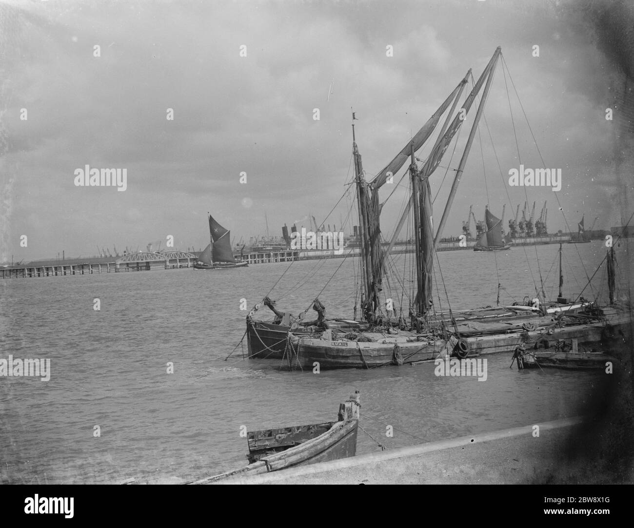 Blick auf die Themse. Die Dockkrane sind in der Ferne zu sehen. Im Vordergrund sind zwei Segelschiffe auf der Flussseite vertäut. 1939 Stockfoto