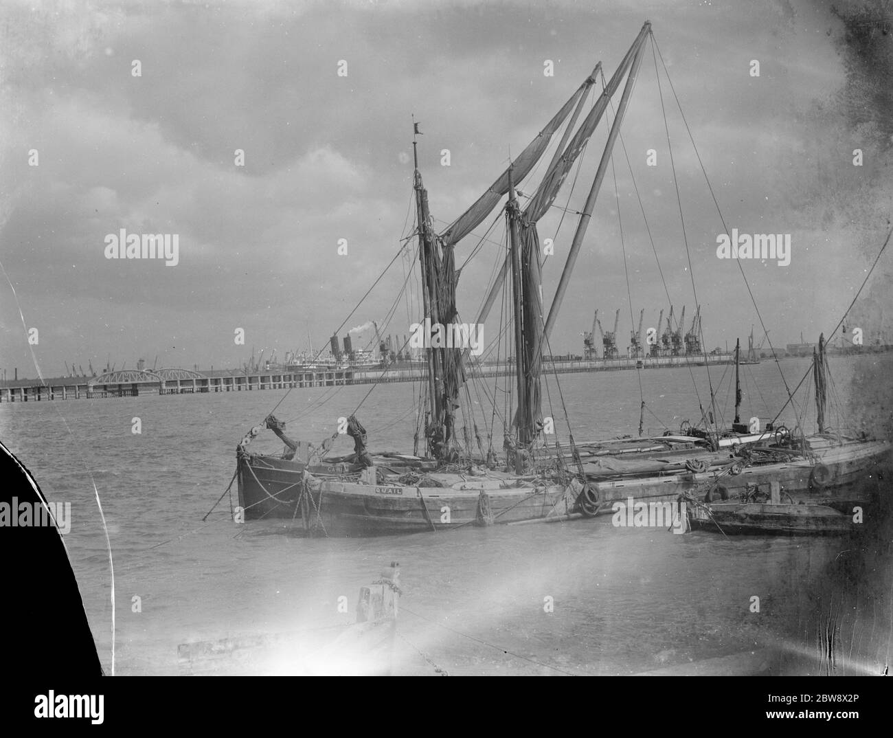 Blick auf die Themse. Die Dockkrane sind in der Ferne zu sehen. Im Vordergrund sind zwei Segelschiffe auf der Flussseite vertäut. 1939 Stockfoto