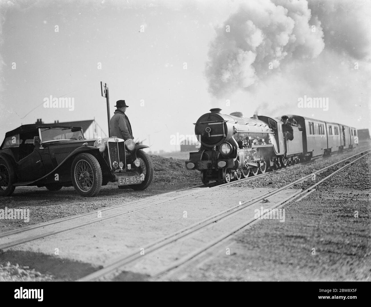 Die Stadtbahn Romney, Hythe & Dymchurch endet am Dungeness Beach. Dieser Motor überquert den Bahnübergang 1939 Stockfoto