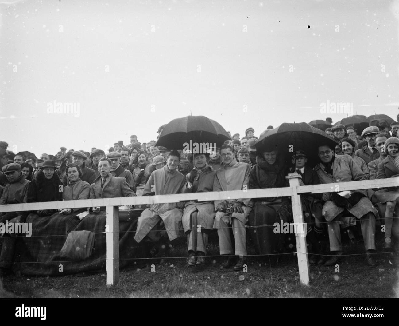 Cray Wanderers Fußballverein gegen Erith Town Fußballverein . Einige der Gäste verstecken sich unter Regenschirmen. 1936 Stockfoto