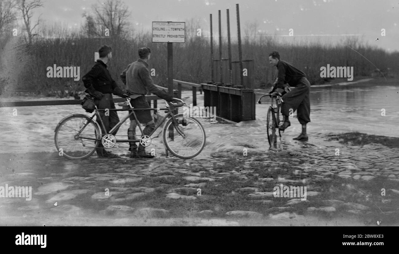 Radfahrer schauen sich die hohen Wasserstände und die Überflutungen an der Schleuse am Fluss in Yalding in Kent an. 1936 Stockfoto