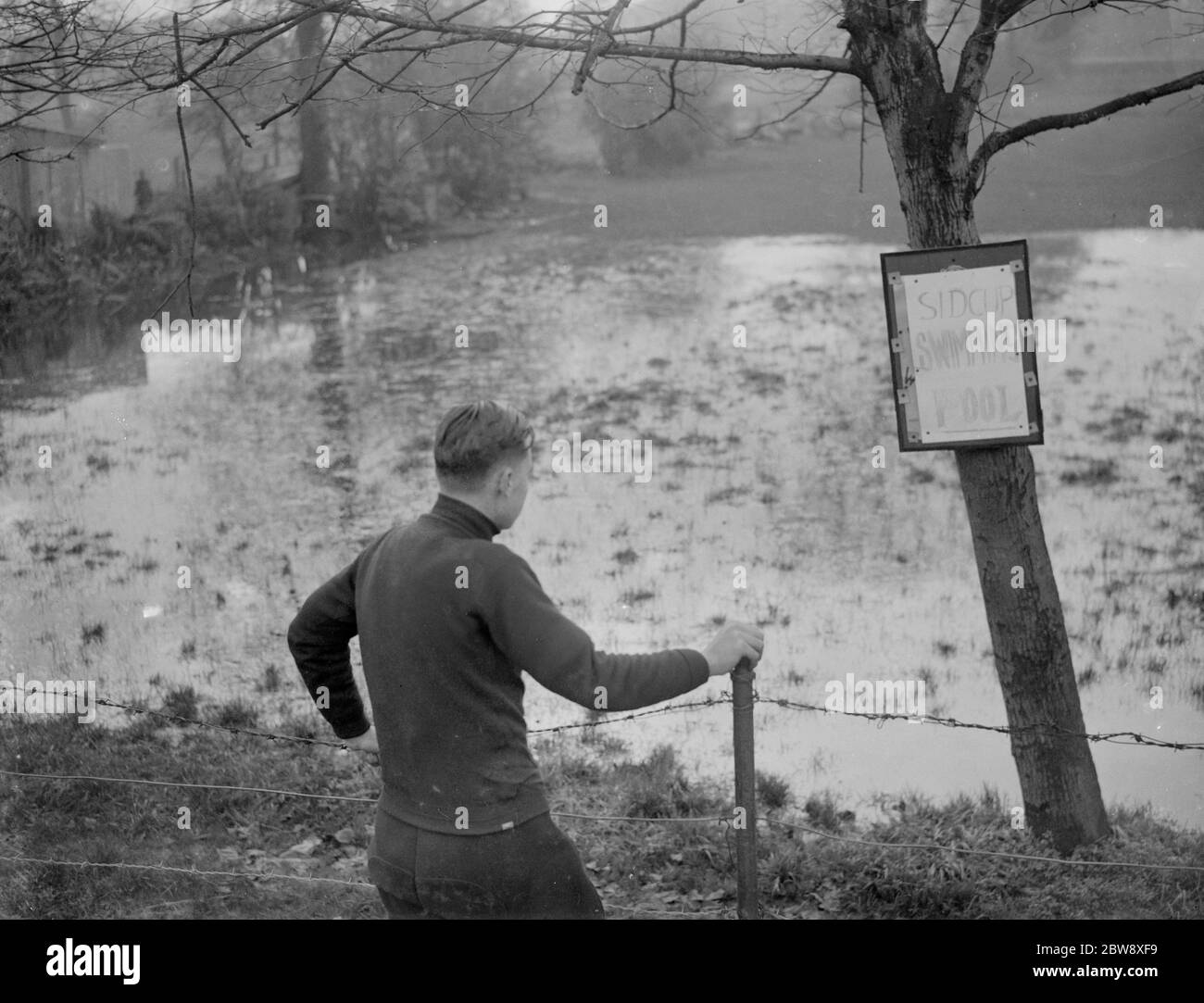 Ein Junge schaut auf das überflutete Sidcup Schwimmbad - überflutet durch das schlechte Wetter. 1936 Stockfoto