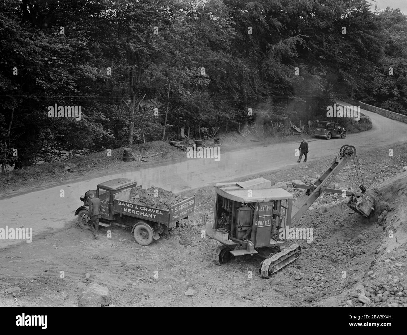Ein Bedford LKW zu T E Streeter, die Sand-und Kieshändler Unternehmen mit Sitz in Dalbeattie, Schottland, wird mit Erde von einem Bagger beladen, auf der Seite der Straße 1936. Stockfoto
