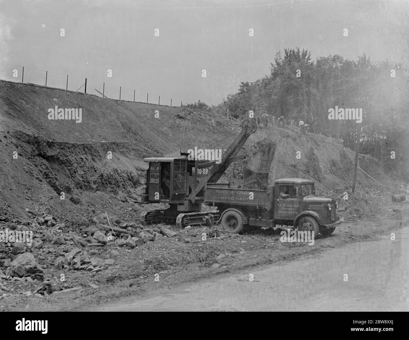 Ein Bedford LKW zu T E Streeter, die Sand-und Kieshändler Unternehmen mit Sitz in Dalbeattie, Schottland, wird mit Erde von einem Bagger beladen, auf der Seite der Straße 1936. Stockfoto