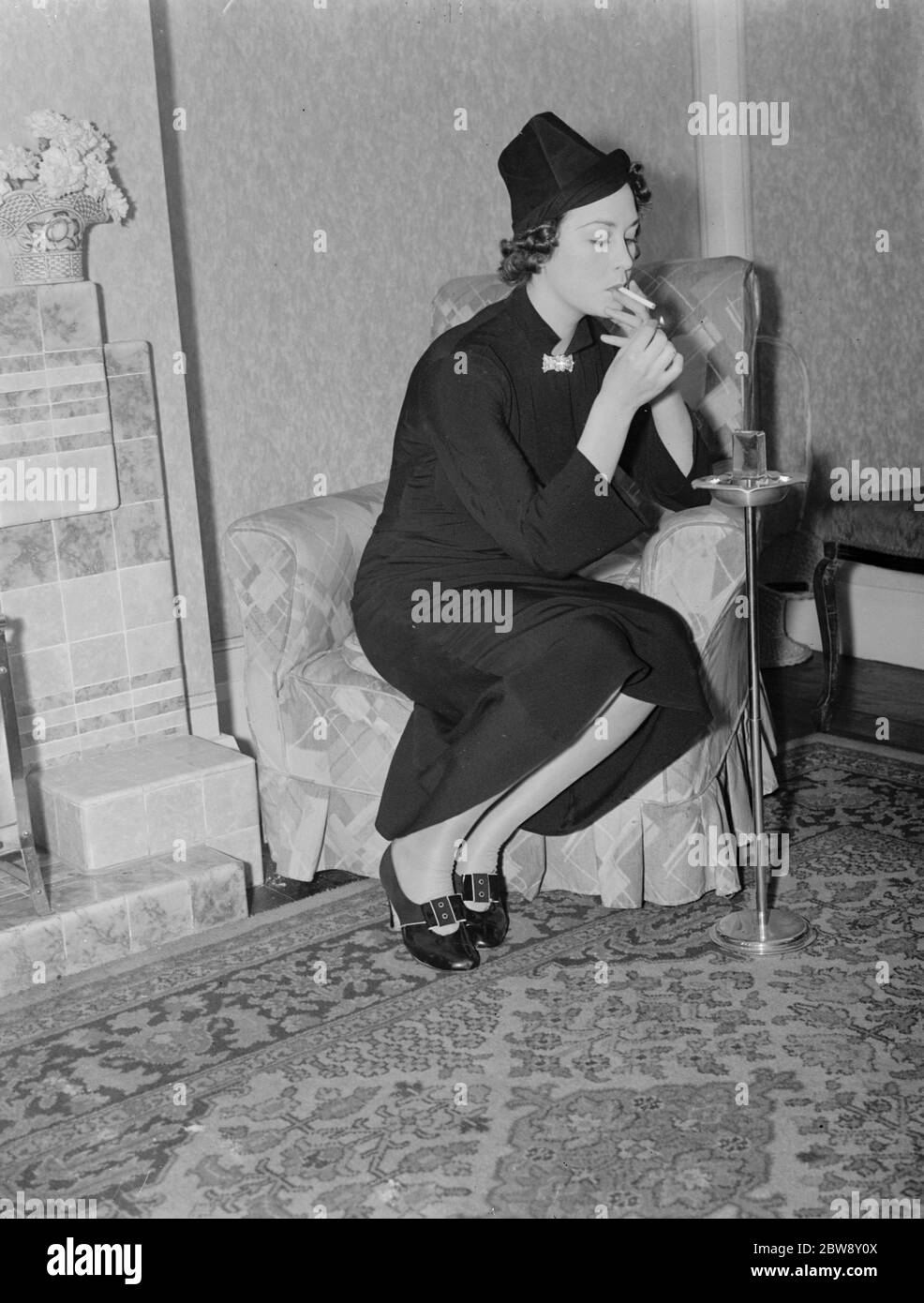 Miss Muriel Oxford sitzt am Feuer und hat eine Zigarette. Stockfoto