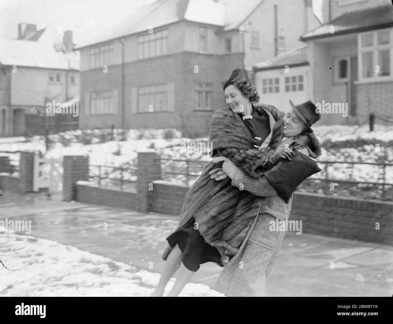 Miss Muriel Oxford wird von einem jungen Mann über den Schnee getragen. 1937 Stockfoto
