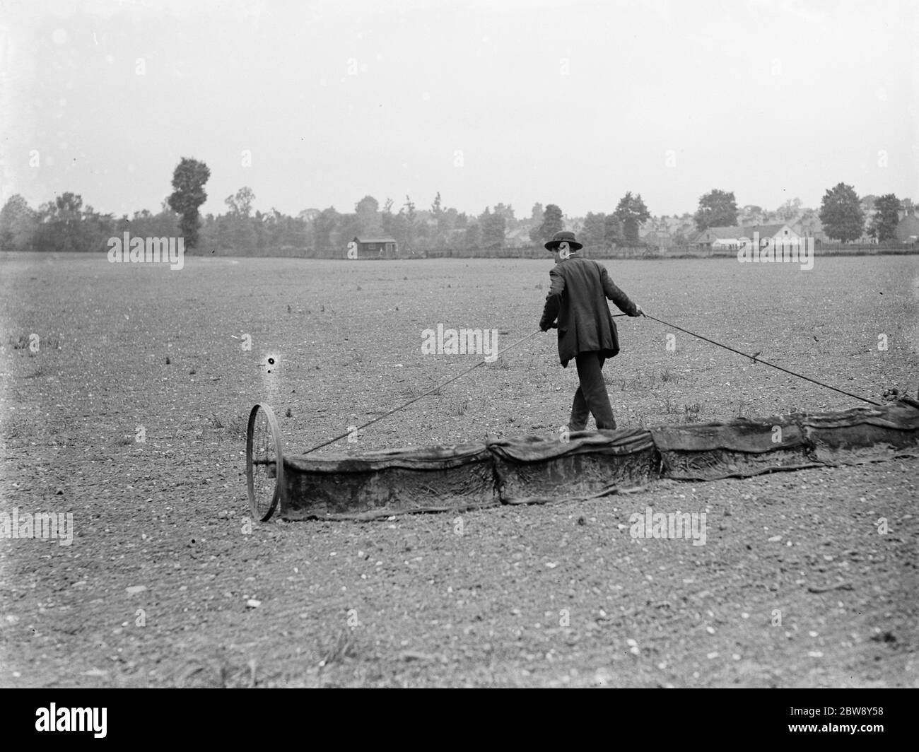 Ein Platzwart zieht einen Rechen über ein Feld. 1936 Stockfoto