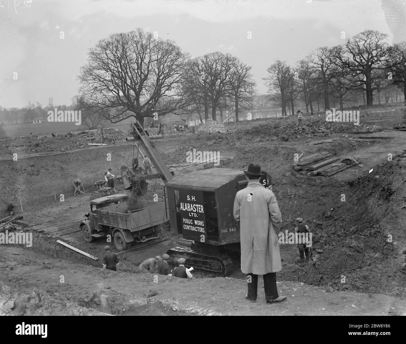 Bagger räumt das Land und setzt Erde in die Rückseite des Bedford LKW, auf dem Gelände des neuen Bexleyheath Schwimmbad in Bexleheath, Kent. 1936 Stockfoto