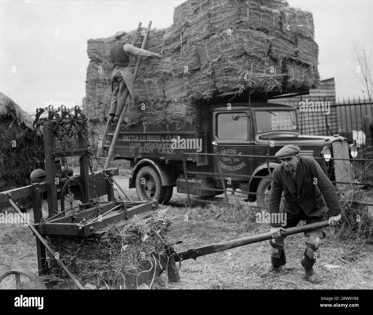 Die Arbeiter von Pattullo Higgs und Co Ltd verwenden eine Presse, um Heuballen zu machen. Sie laden sie dann auf ihren LKW der Firma Bedford in St Mary Cray, Kent. 21 Februar 1936 . Stockfoto