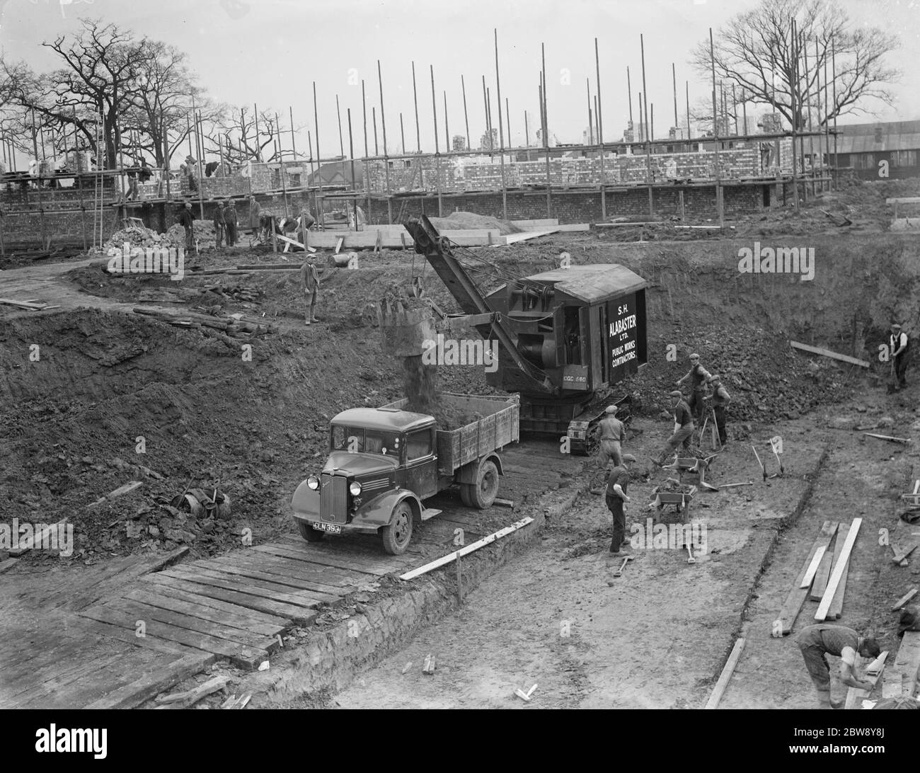Bagger räumt das Land und setzt Erde in die Rückseite des Bedford LKW auf dem Gelände des neuen Bexleyheath Schwimmbad in Bexleyheath , Kent . 1936 Stockfoto