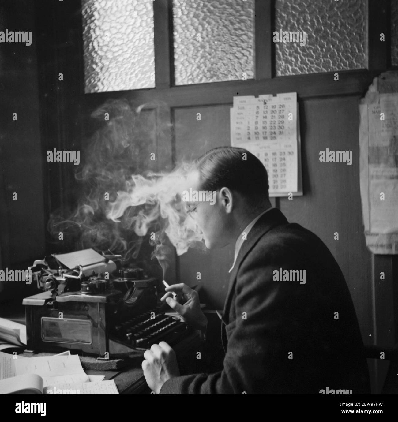 Herr Fassam raucht eine Zigarette, während er an einer Schreibmaschine arbeitet. 1939 Stockfoto