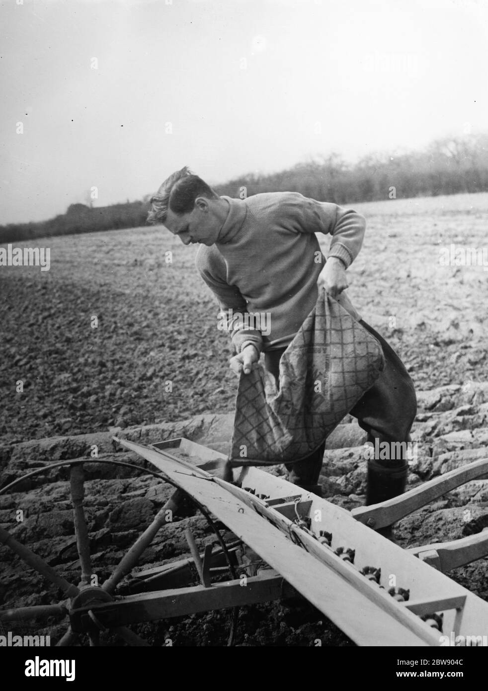 Landwirt Laden Samen aus einem Sack in einen Cooper 's Drymac Saatgut Barrow . 1937 Stockfoto