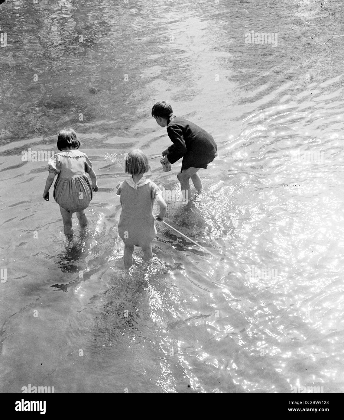 Kleine Kinder paddeln in der ford an der Eynsford Buckelbrücke über den Fluss Darent in Kent. 1939 . Stockfoto