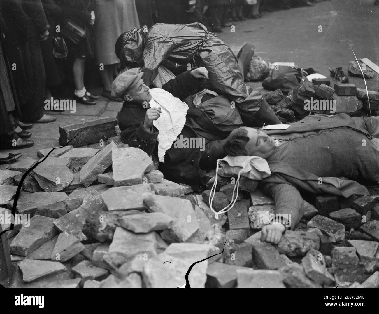 Vorsorgeübung mit Luftangriff auf der Old Kent Road in London. Zuschauer schauen auf, wie die "Opfer" während der Übung tendenziell sind. 1939 . Stockfoto