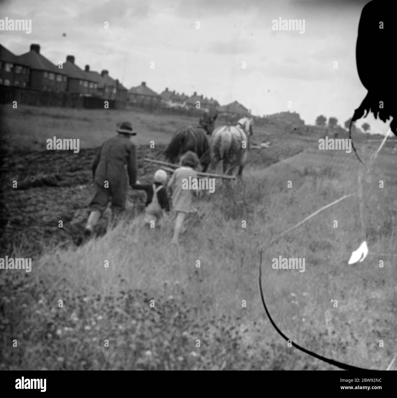 Kinder folgen einem Bauern und seinem Pferdeteam beim Pflügen eines Feldes in New Eltham, London. 1939 . Stockfoto