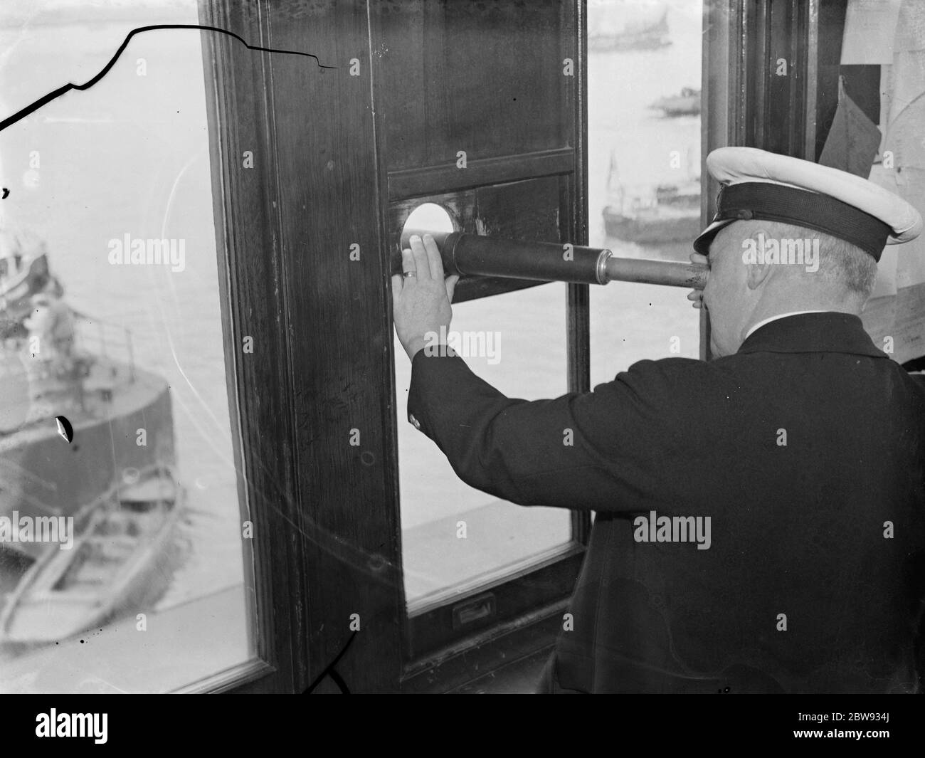 Thames Piloten in Gravesend, Kent, die Schiffen helfen, durch die verstopften Gewässer des Hafens zu navigieren. Herr W Simmons schaut aus seinem Zimmer durch sein Handteleskop. 1939 Stockfoto