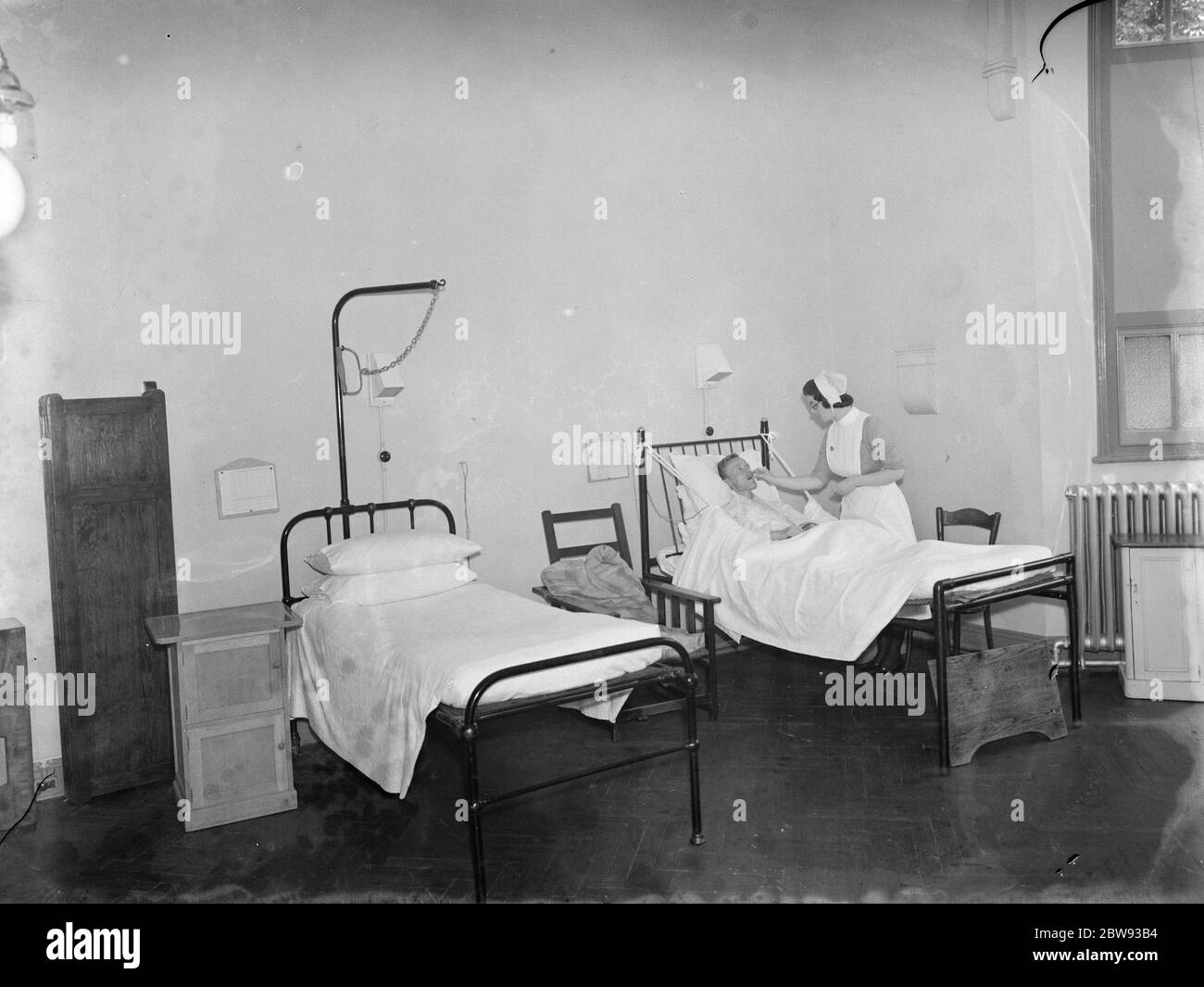 Das Sidcup Cottage Hospital in Kent. Eine Krankenschwester neigt zu einem Patienten in der Männerabteilung. 1939 Stockfoto