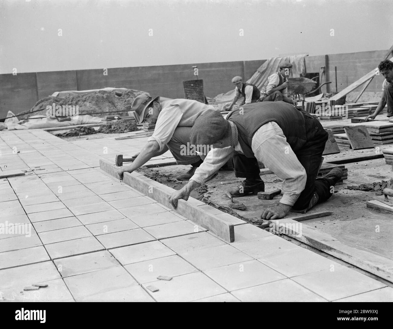 Arbeiter von Val De Travers Asphalt Limited, ein Pflasterunternehmen, arbeiten auf einem Dach in Greenwich, London. 1938 Stockfoto