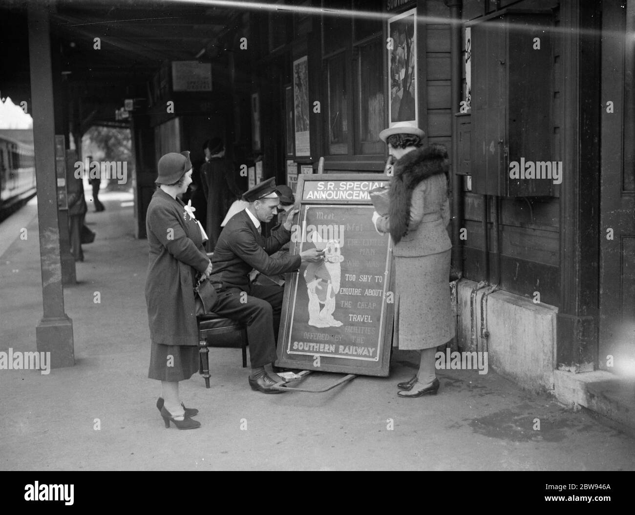 Die Leute versammeln sich, um dem Eisenbahnportier Zeichenschreiber Mr. E A Burgar zuzusehen. 1938 Stockfoto