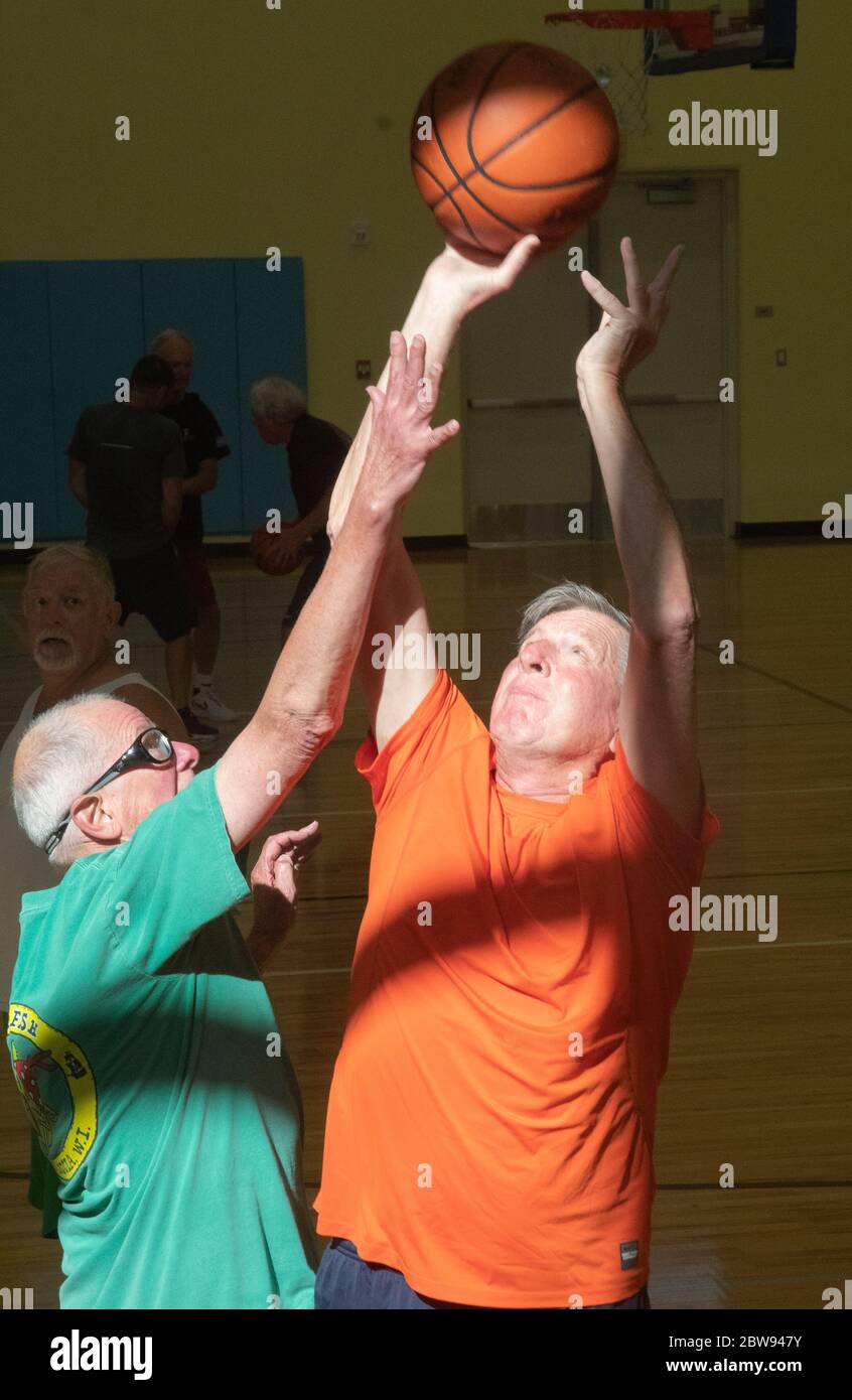 Ein älterer Basketballspieler macht einen Sprung, während ein anderer Spieler versucht, ihn im Erholungszentrum in Englewood, Florida, USA zu blockieren. Stockfoto