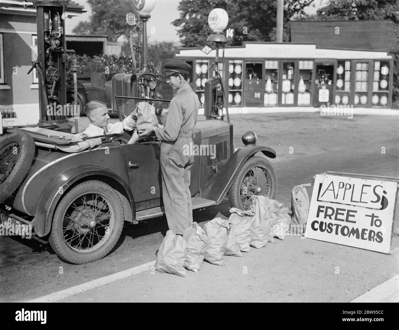 Ein Junge gibt kostenlose Äpfel an Kunden in einem kleinen Garge. 1936 . Stockfoto