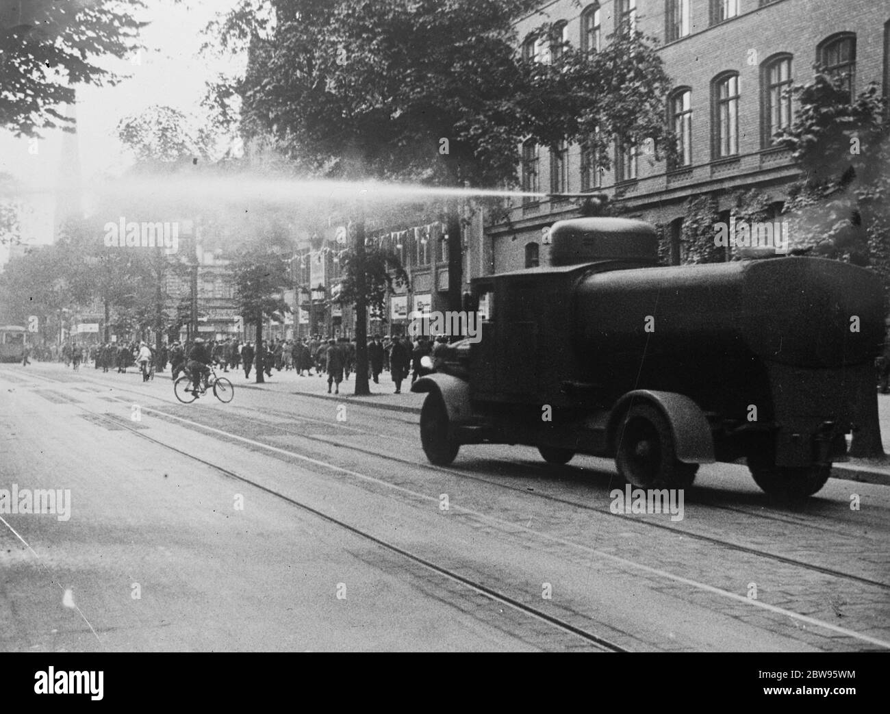 Die Polizei fährt mit Wasserbrötchen Randalierer aus Berliner Straßen. Mit mächtigen Wasserpistolen, montiert auf gepanzerten Lastwagen, fuhr die Polizei randalierenden Nazis und Kommunisten von den Straßen. Hunderte von Polizisten in Autos und Lastwagen wurden in die Vororte von Berlin, wo die Unruhen stattgefunden haben, eilig. Polizisten in Lastwagen werden zum Schauplatz der Störung in einem Vorort von Berlin gefahren. 27 Juni 1932 Stockfoto