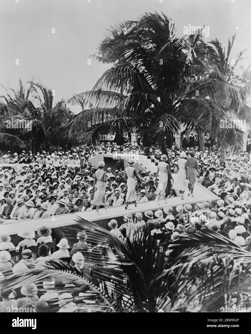 Eine Modeparade im Sonnenschein, während London zittert. Während London und ganz England unter Eis und Schnee zittern, werden in Miami Beech, Florida, Modeparaden in strahlendem Sonnenschein abgehalten. Mannequins Parading vor Sommer gekleideten Massen in den Palmengärten in Miami Beech, Florida. 11 Februar 1932 Stockfoto