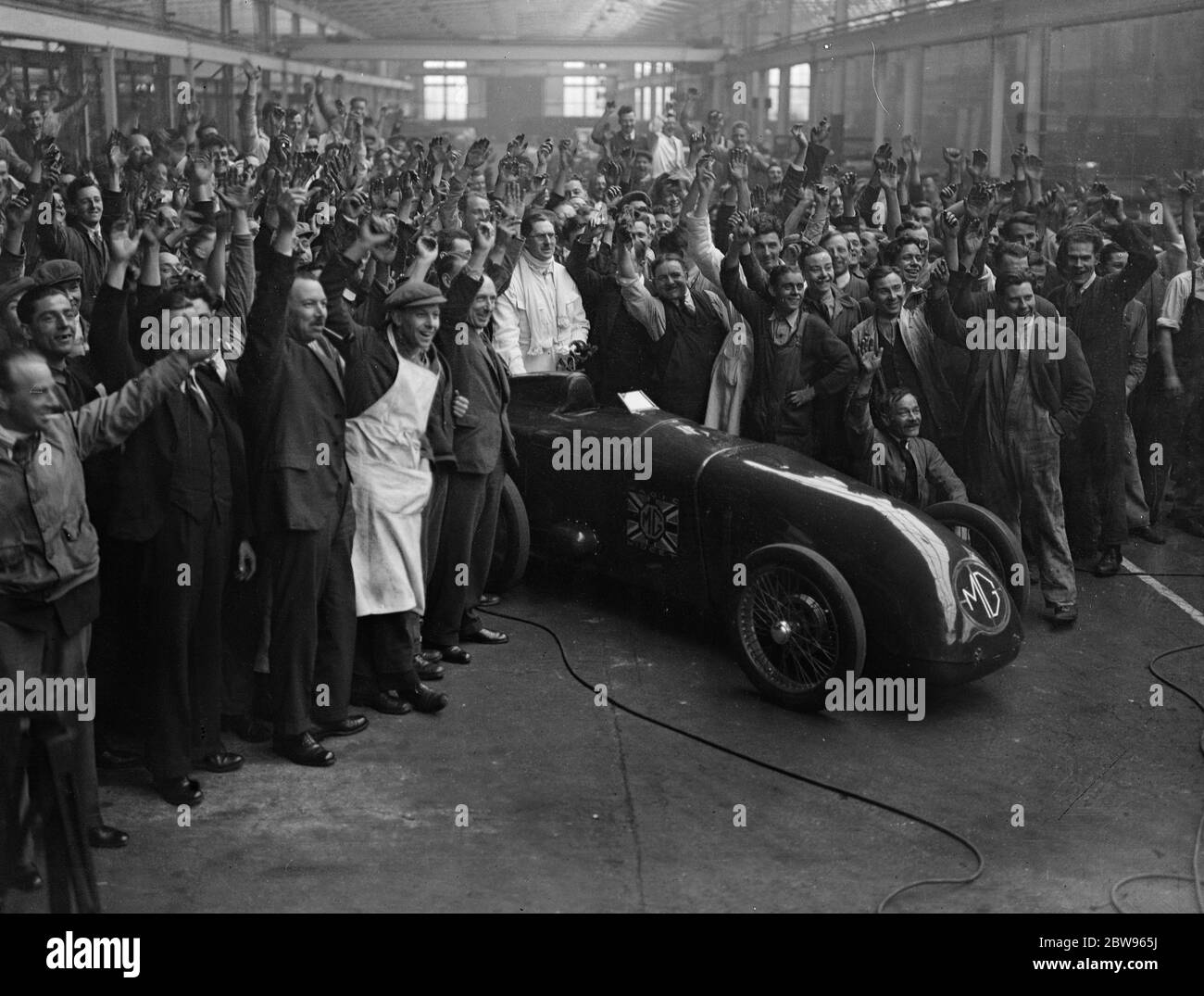 G E T Eyston bereitet sich auf Angriff auf Weltrekord für Baby-Autos in Pendine Sands . Herr G E T Eyston, der Rennfahrer, macht die letzten Vorbereitungen für seinen Versuch, einen neuen Weltrekord für Baby-Autos mit seinem MG The Magic Midget, die auf Pendine Sands, Carmarthenshire, Wales stattfinden wird. Er wird einen speziell angefertigten Asbestanzug tragen. Das Auto wird angefeuert, als es die Abingdon-Garage verließ, wo es gebaut wurde, für Pendine, Wales. Februar 1932 Stockfoto
