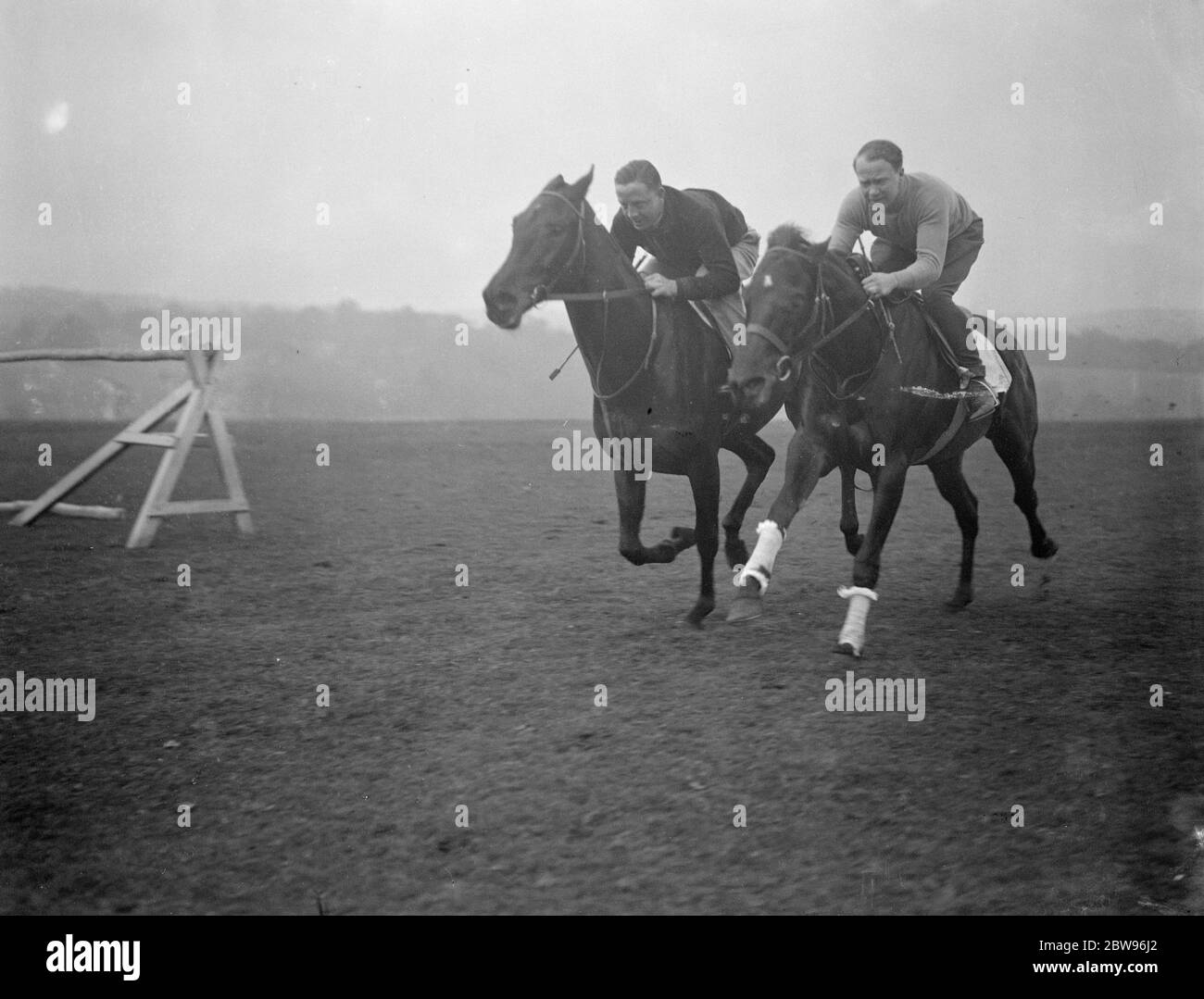 Neuer Epsom Trainer beginnt die Arbeit für die großen Rennen. Eine Lizenz zum Zug wurde gerade von der Jockey Club Herrn Arthur S Boxall , ein bekannter North London Estate Agent , der in Epsom gelebt hat und besaß Pferde für eine Reihe von Jahren gewährt. Herr Boxall führt seine Trainingsarbeit in den sehr frühen Morgenstunden und hat einige wahrscheinlich Kandidaten in Vorbereitung auf die großen Rennen in diesem Sommer , einschließlich Sprint , der in der Stadt und im Vorburban engagiert . Herr Arthur Boxall auf Sprint (rechts) begleitet von einem anderen seiner Pferde Prince Charming, in einem frühen Morgen Galopp auf Epsom Downs. April 1932 Stockfoto