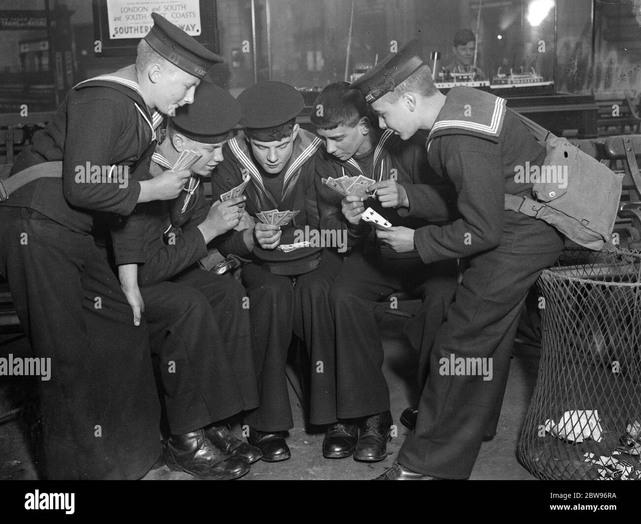 Warten Sie die Zeit in waterloo . Jungs vom Trainingsschiff HMS Warspite genießen ein Kartenspiel, während sie auf den Zug am Bahnhof Waterloo in London warten, zu Beginn ihrer Osterferien. 24 März 1932 Stockfoto