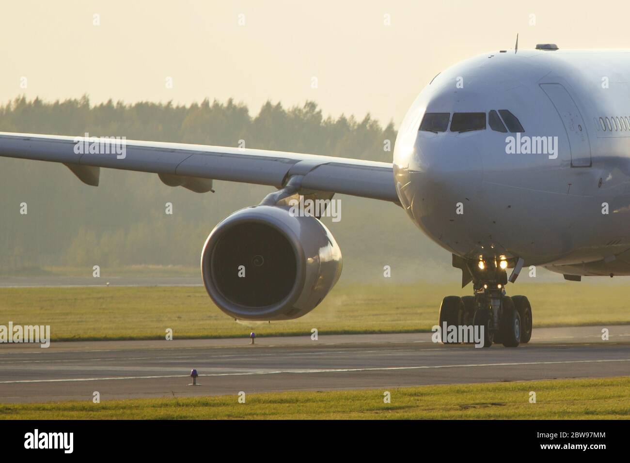 Nahaufnahme eines Großkörperflugzeugs, das während des Sonnenuntergangs auf der Landebahn rollt. Flugzeug schaltet auf Start- und Landebahn. Sehr heiße Luft hinter dem Flugzeugmotor. Transpor Stockfoto