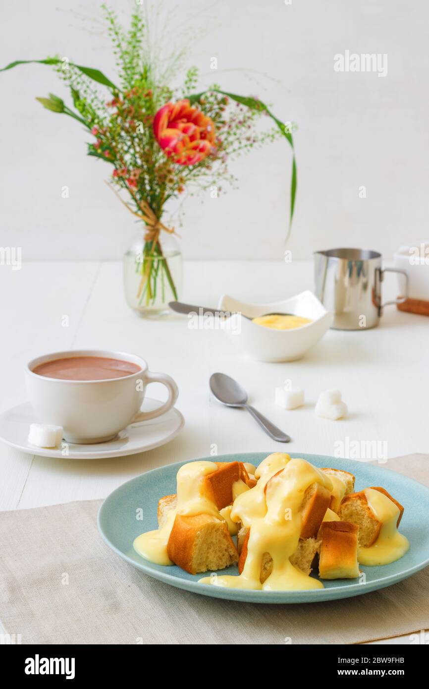 Hefepastete Brötchen mit Zabaglione oder Vanillecreme, oder Eierlikör, süßes Dessert oder Hauptgericht. Weißer Holztisch Hintergrund. Stockfoto