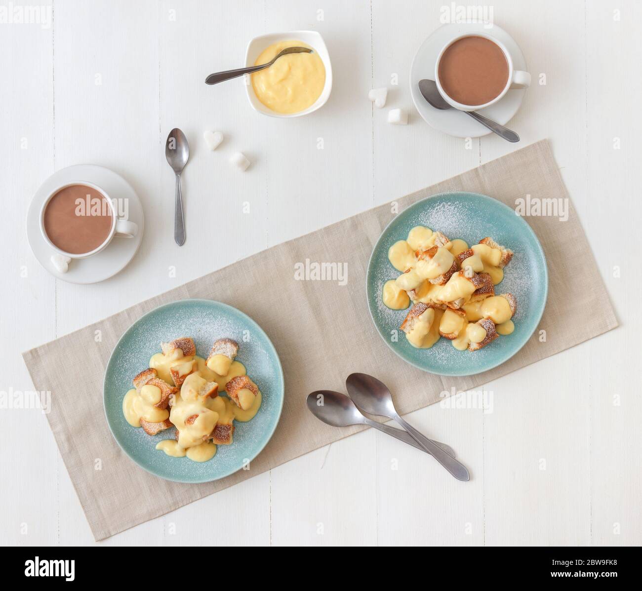 Hefegebäck mit Zabaglione oder Vanillecreme oder Eierkuchen, süßem Dessert oder Hauptgericht. Weißer Holztisch Hintergrund. Draufsicht. Stockfoto