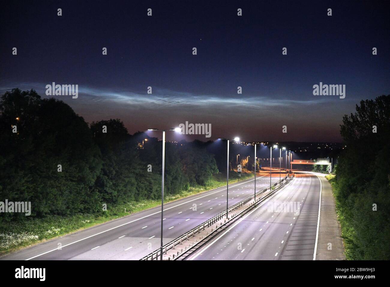 West Bromwich, West Midlands, 31. Mai 2020. Ein Blick von der Autobahn M5 von West Bromwich, Richtung Walsall mit seltenen Nachtakten Wolken beleuchtet in den Nachthimmel. Die schwachen wolkenähnlichen Phänomene bilden sich nur in der oberen Erdatmosphäre. Im Gegensatz zu den niederen Wolken, die mit dem Wetter in Verbindung stehen, bilden sich diese Wolken sehr hoch, etwa 85,300 Meter (53 Meilen) über der Erdoberfläche, in der Mesosphäre. Sie bestehen wahrscheinlich aus gefrorenem Wasser oder Eiskristallen und sind nur in der astronomischen Dämmerung sichtbar. Das Wort noctilucent bedeutet im Lateinischen ungefähr ‘Nachtschienen'. Dies sind die höchsten Clou Stockfoto