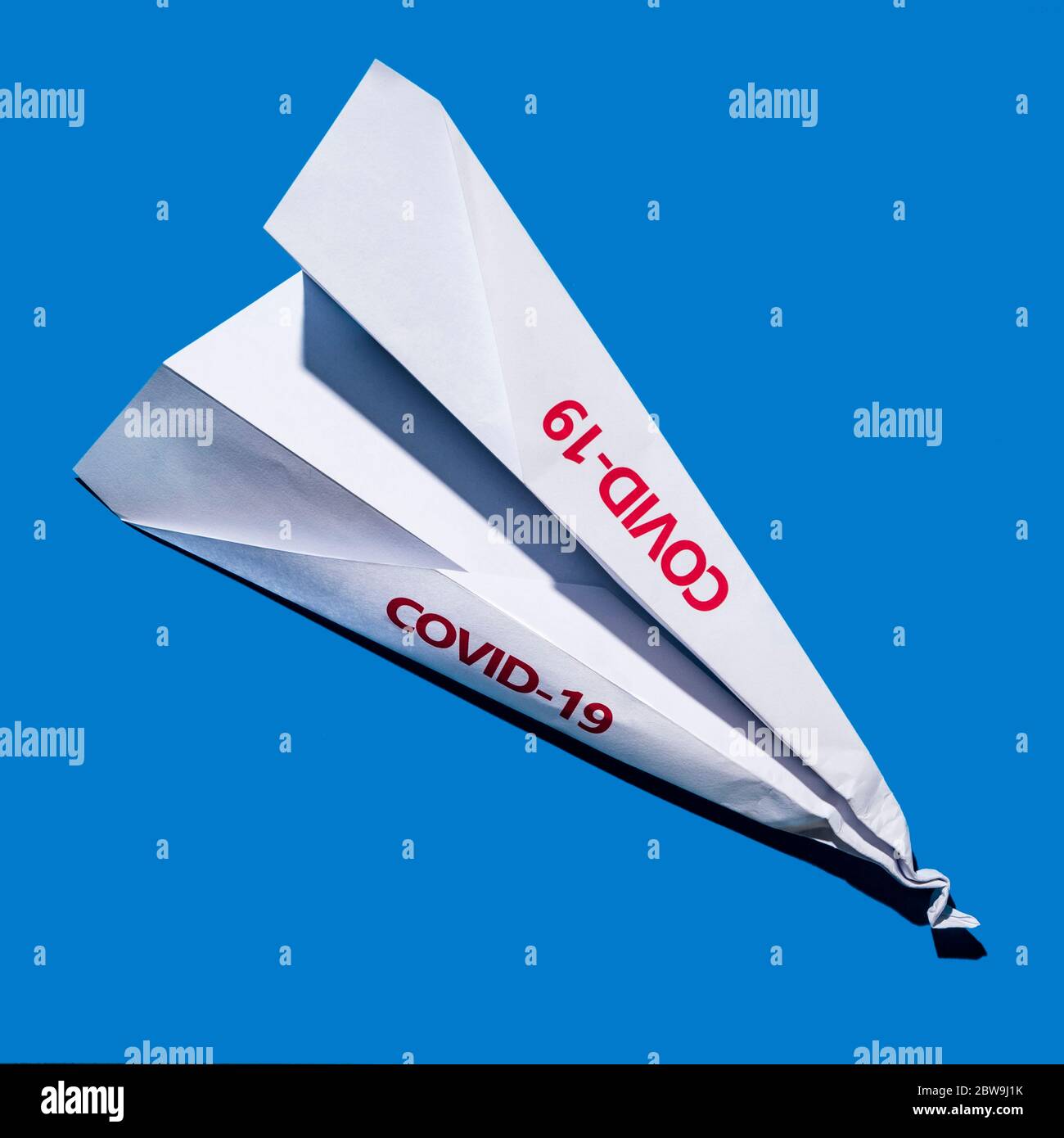 Studioaufnahme eines Papierflugzeugs mit Covid-19-Schild Stockfoto
