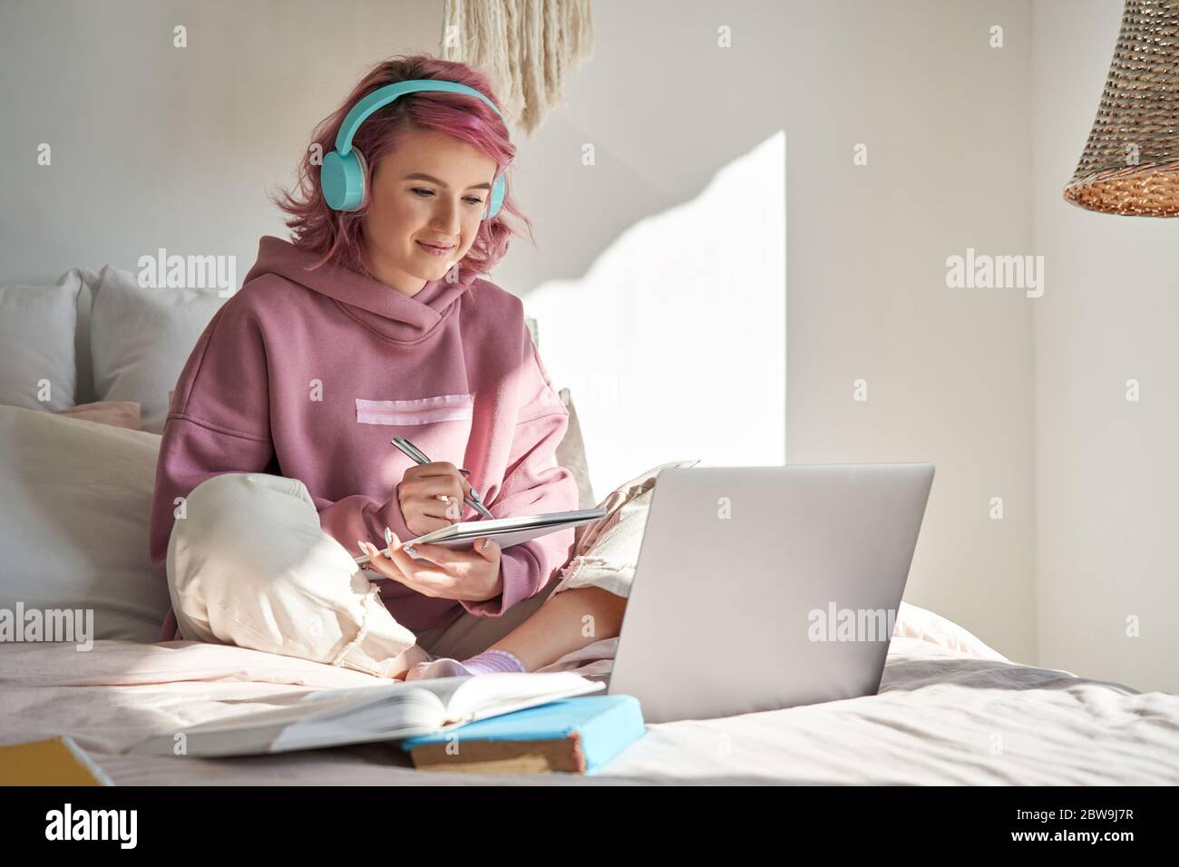 Hipster teen Mädchen Student mit rosa Haar online Webinar lernen im Bett. Stockfoto