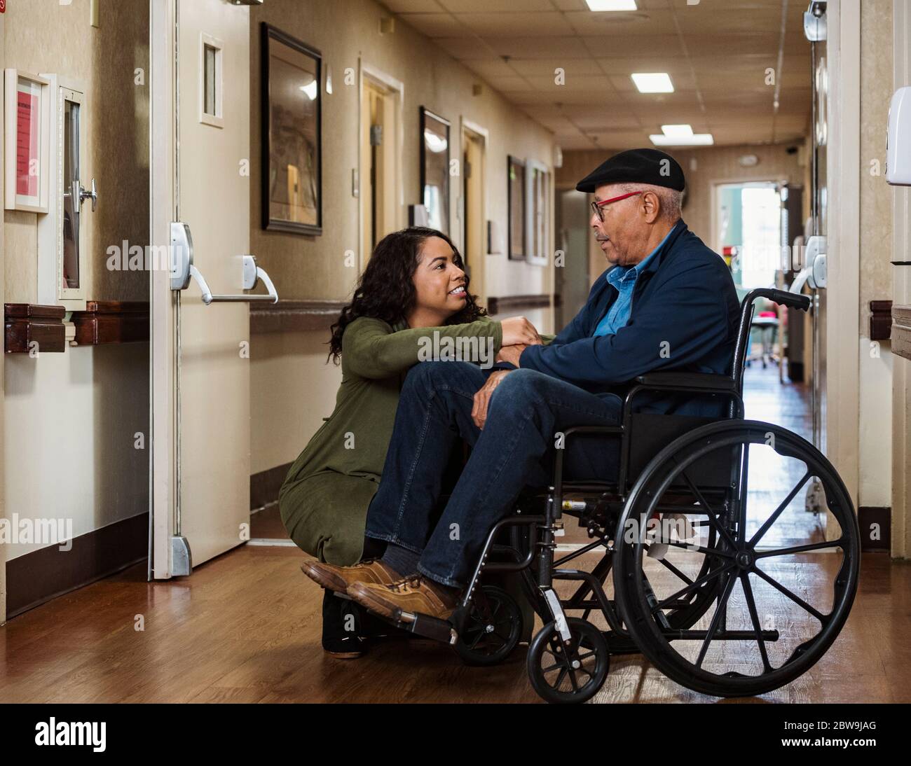 Tochter, die Hände mit dem älteren Vater im Rollstuhl hält Stockfoto