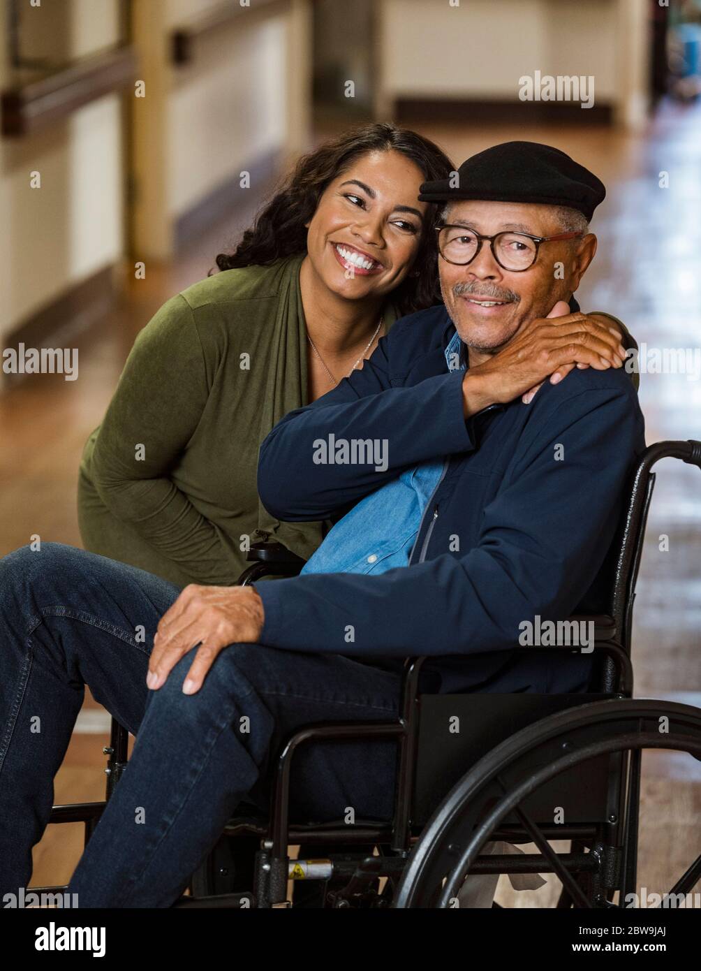 Tochter umarmt älteren Vater im Rollstuhl Stockfoto