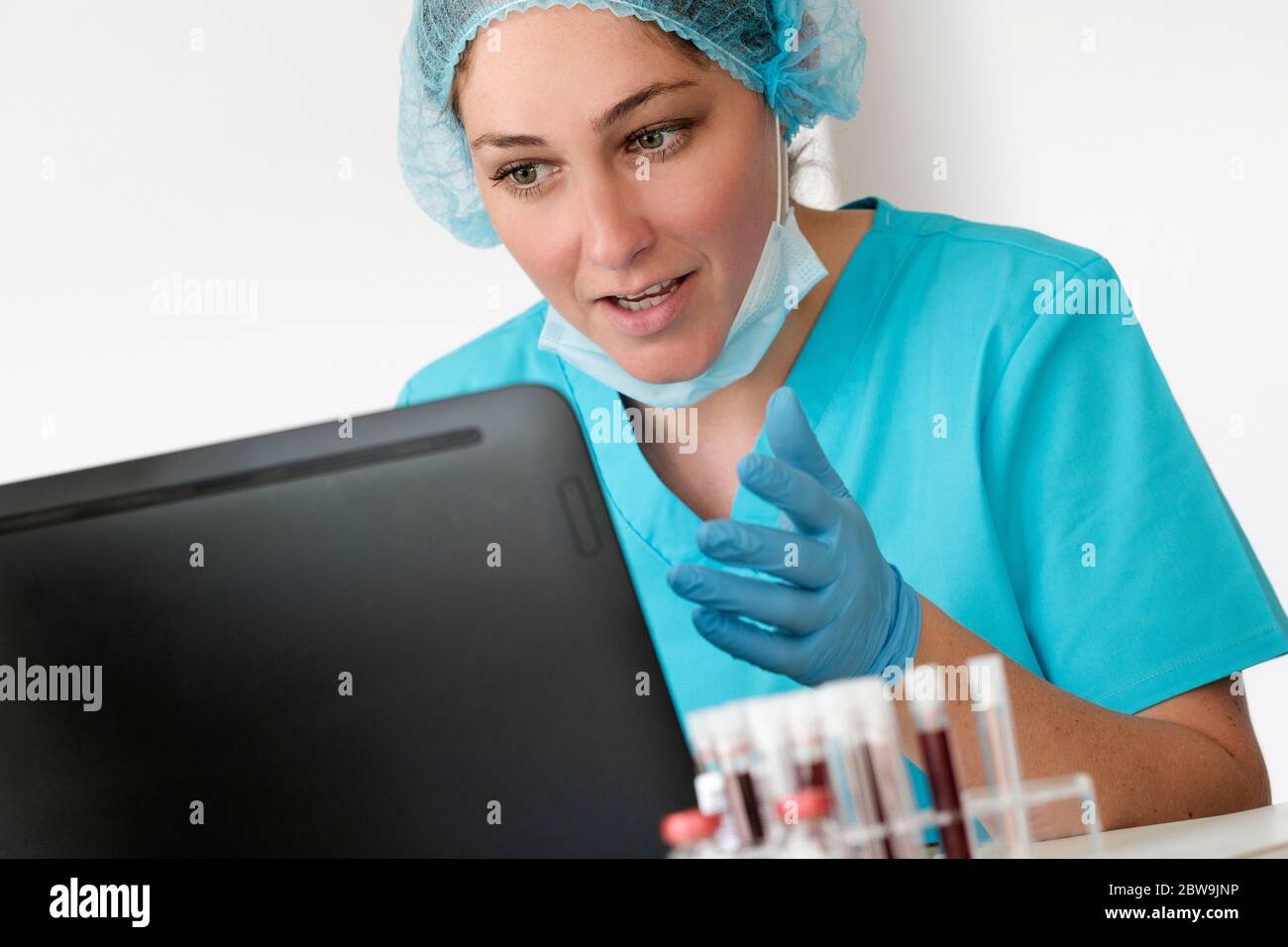 Frau in schützenden labÂ workwearÂ sitzt vor dem Laptop Stockfoto