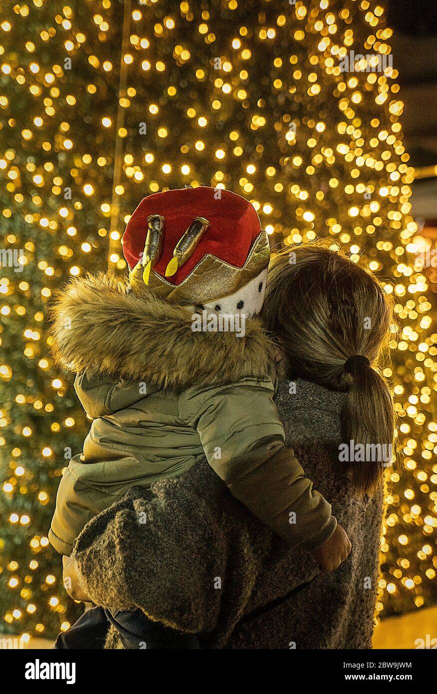 Mutter und Sohn beobachten beleuchteten Weihnachtsbaum Stockfoto