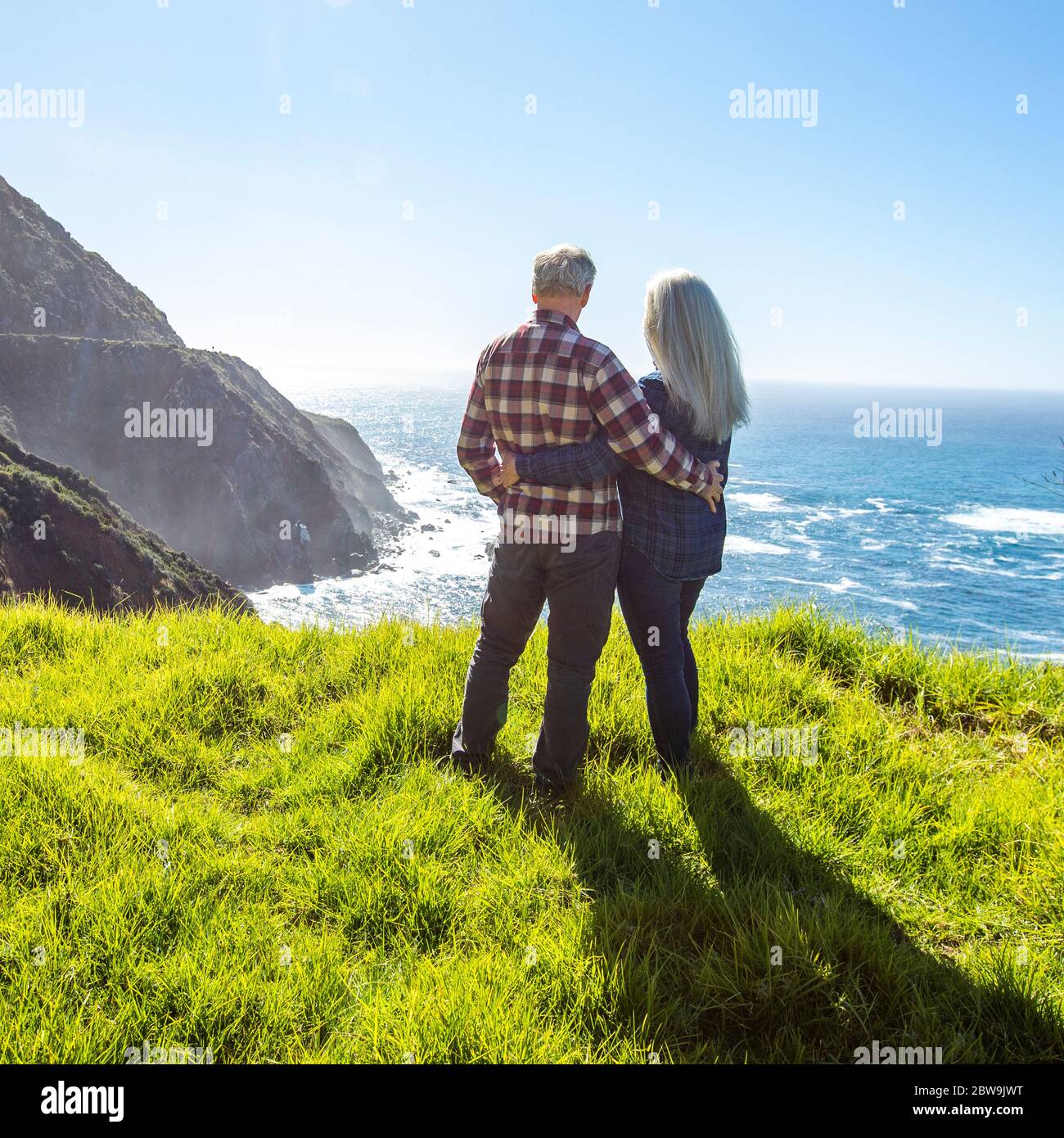 USA, Kalifornien, Big Sur, älteres Paar, das den Ozean von einer grasbewachsenen Klippe aus beobachtet Stockfoto
