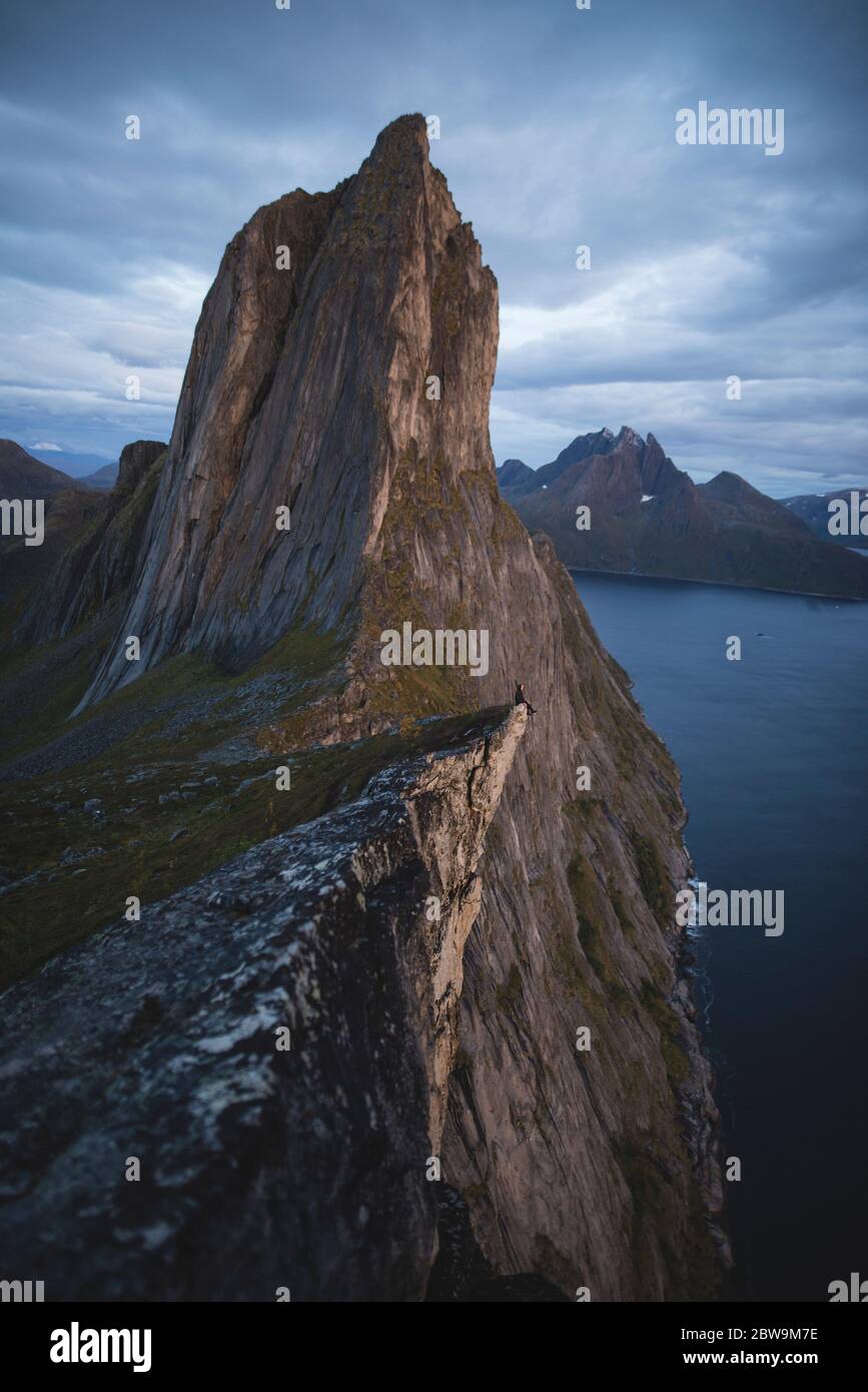 Norwegen, Senja, Mann sitzt auf der Klippe Kante nearÂ SeglaÂ Berg Stockfoto