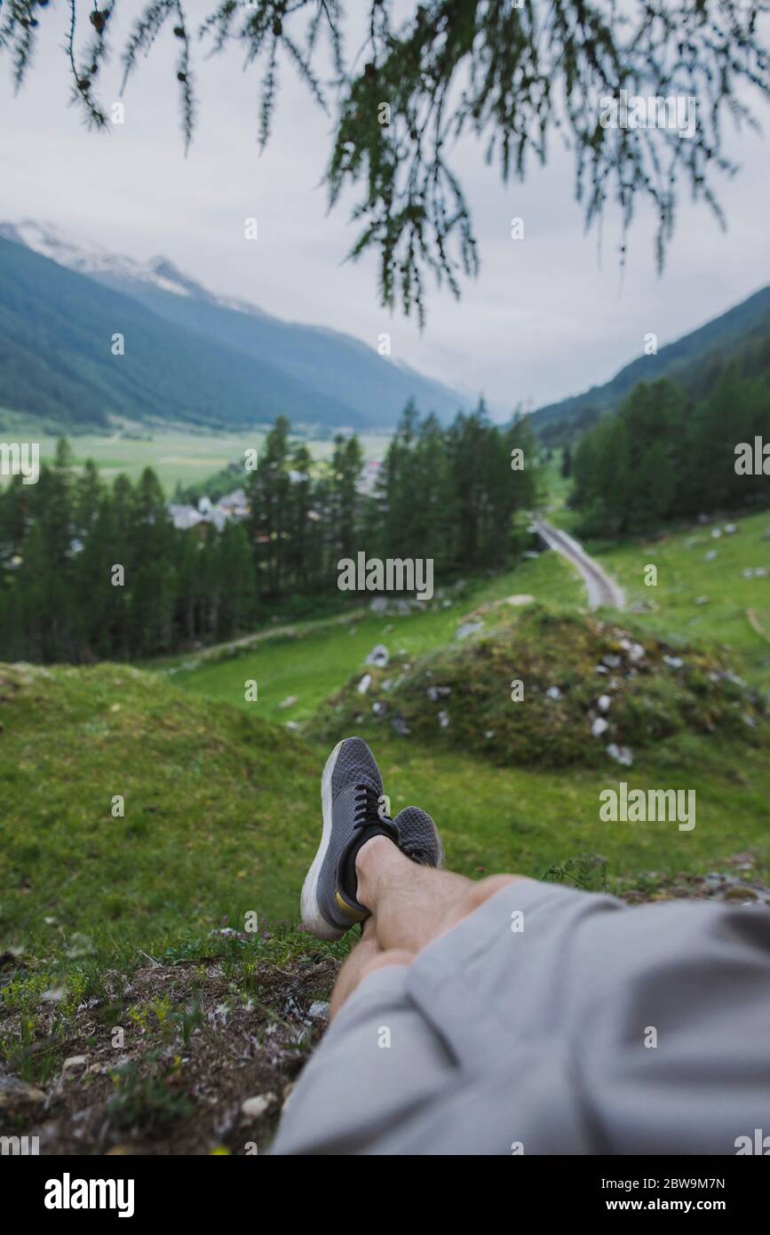 Schweiz, Obergoms, Männerbeine, die sich auf dem Gras in den Schweizer Alpen entspannen Stockfoto