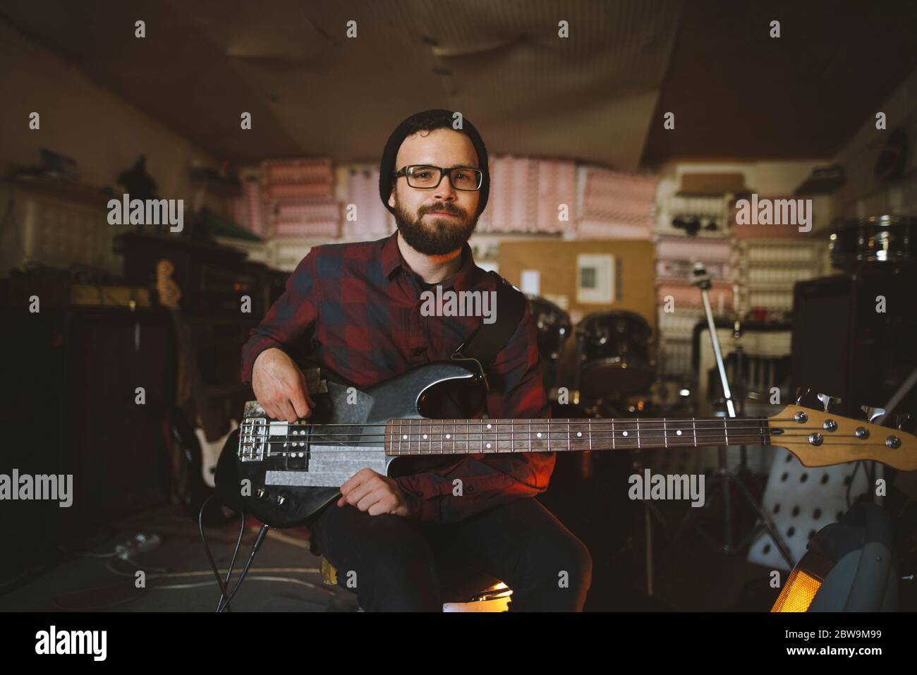 Junger Mann spielt Bass-Gitarre bei der Probe in der Garage Stockfoto
