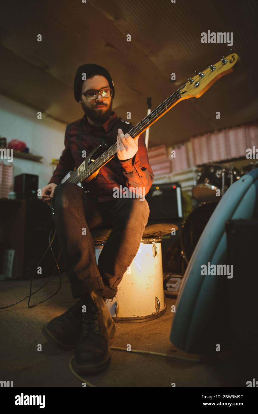 Junger Mann spielt Bass-Gitarre bei der Probe in der Garage Stockfoto