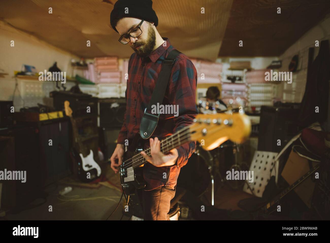 Junger Mann spielt Bass-Gitarre bei der Probe in der Garage Stockfoto