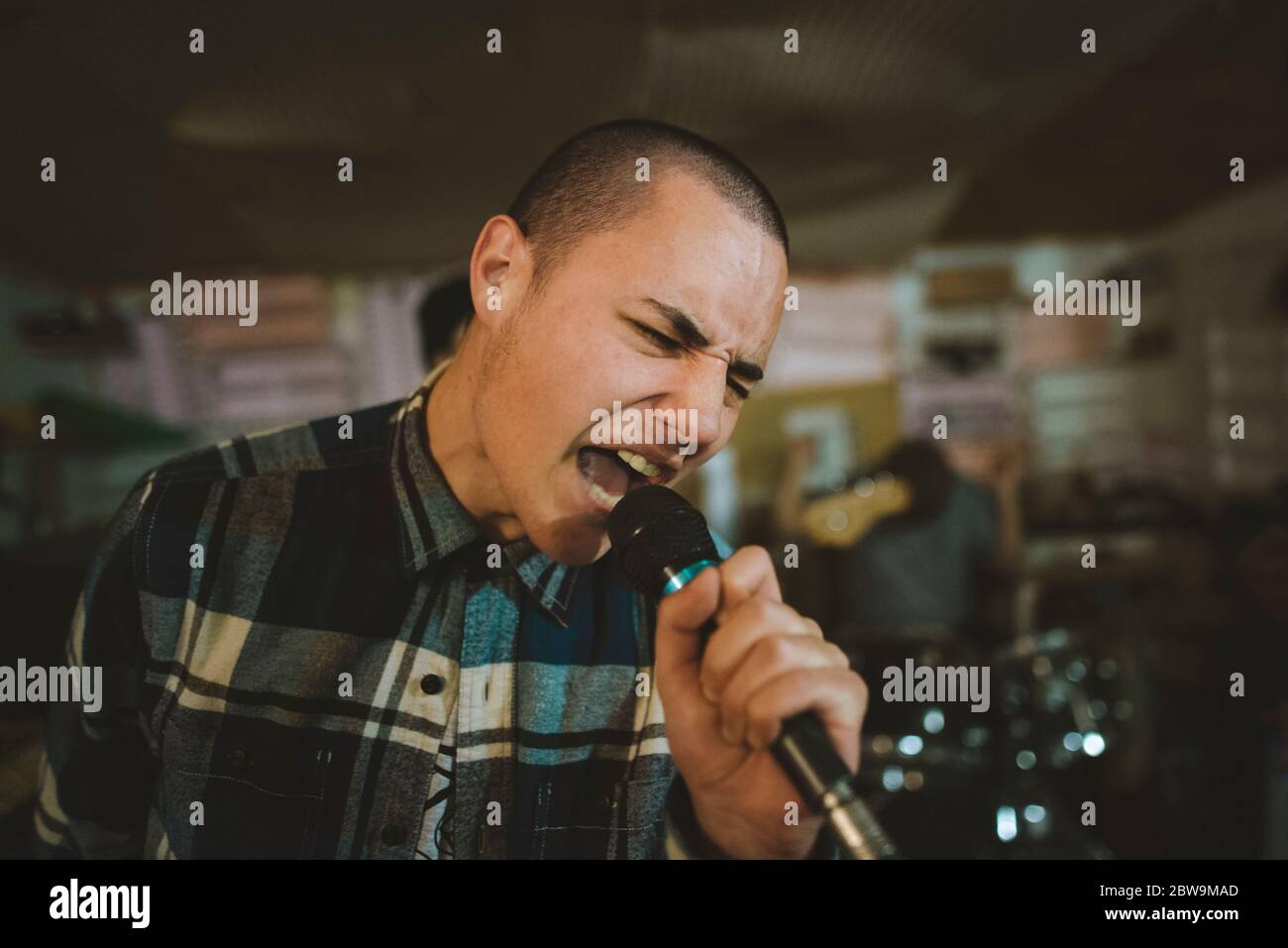 Junger Mann singt während der Probe in der Garage Stockfoto