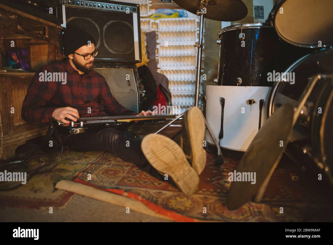 Junger Mann spielt Bass-Gitarre bei der Probe in der Garage Stockfoto