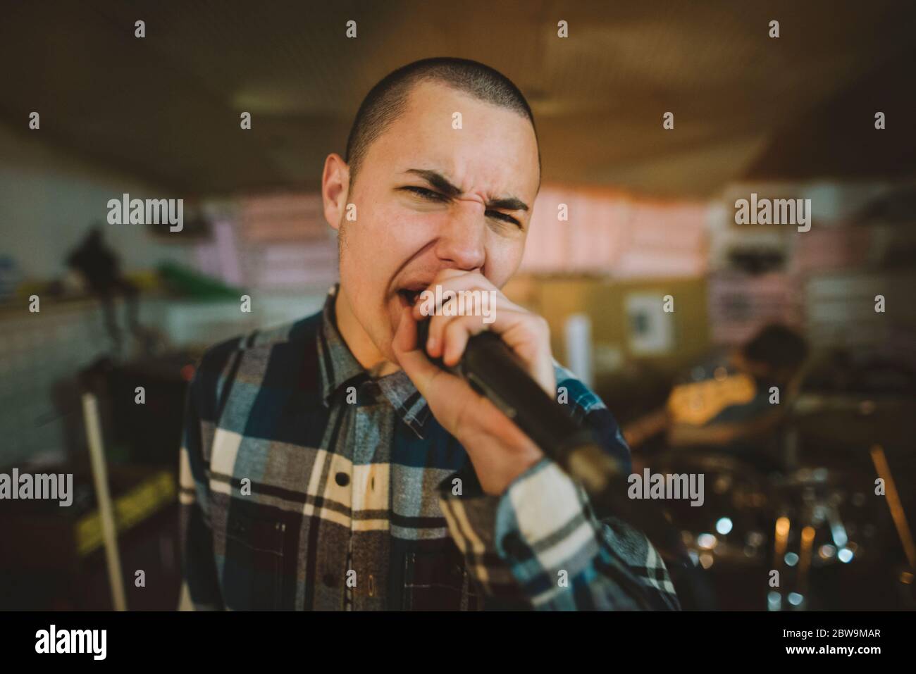 Junger Mann singt während der Probe in der Garage Stockfoto