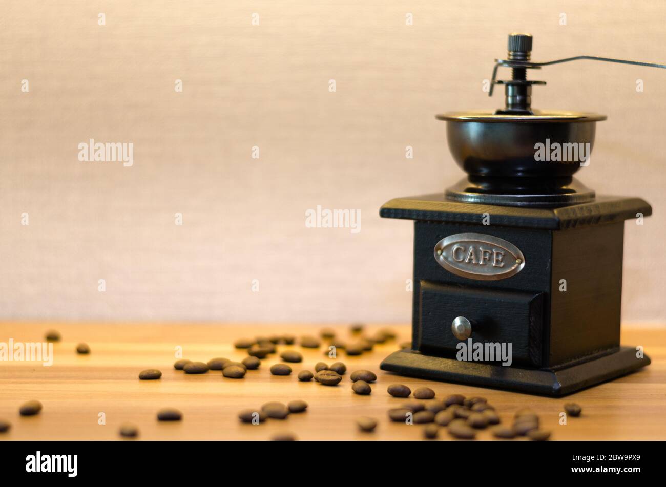 Eine Kaffeemühle mit einer offenen Schublade und unordentlichen Kaffeebohnen auf einem Holztisch. Stockfoto